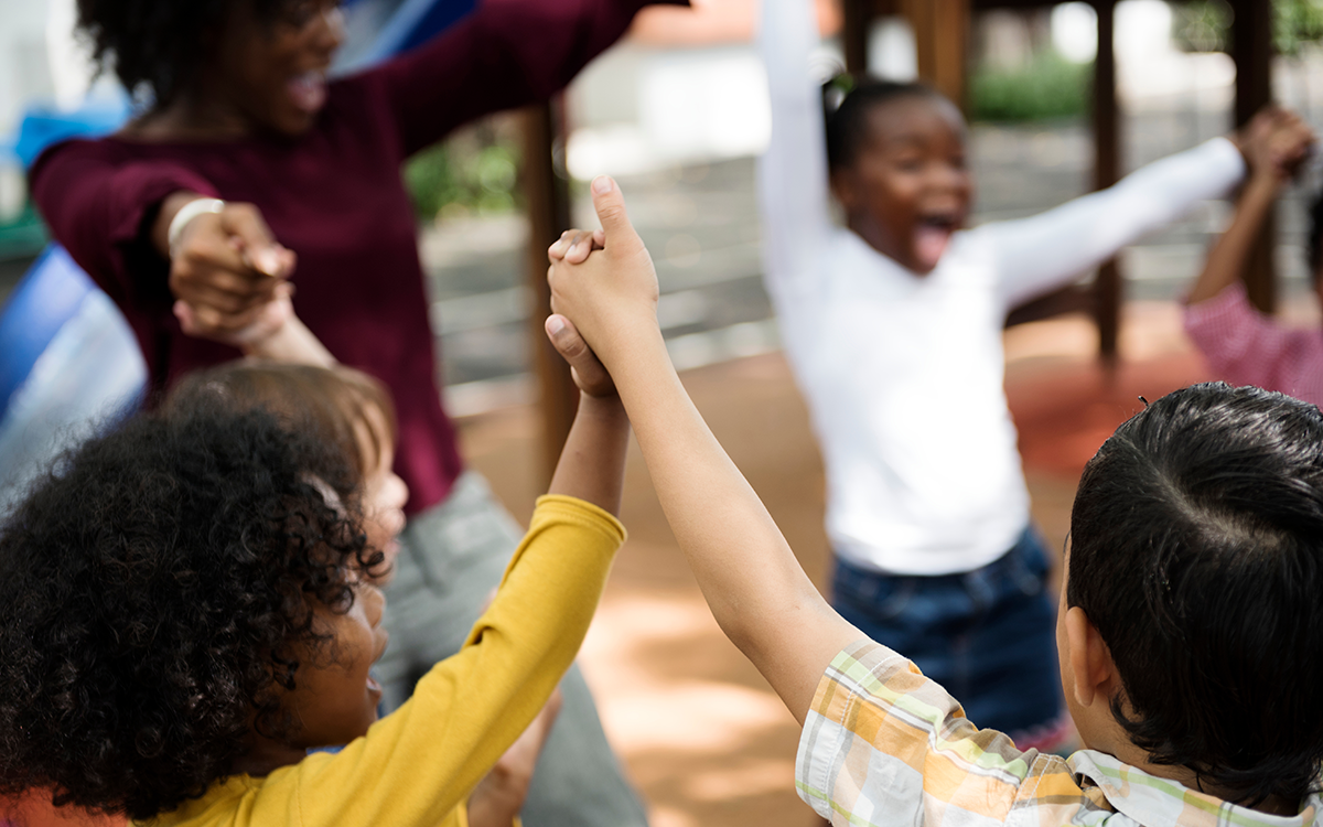 Kids and an adult holding raised hands in a circle