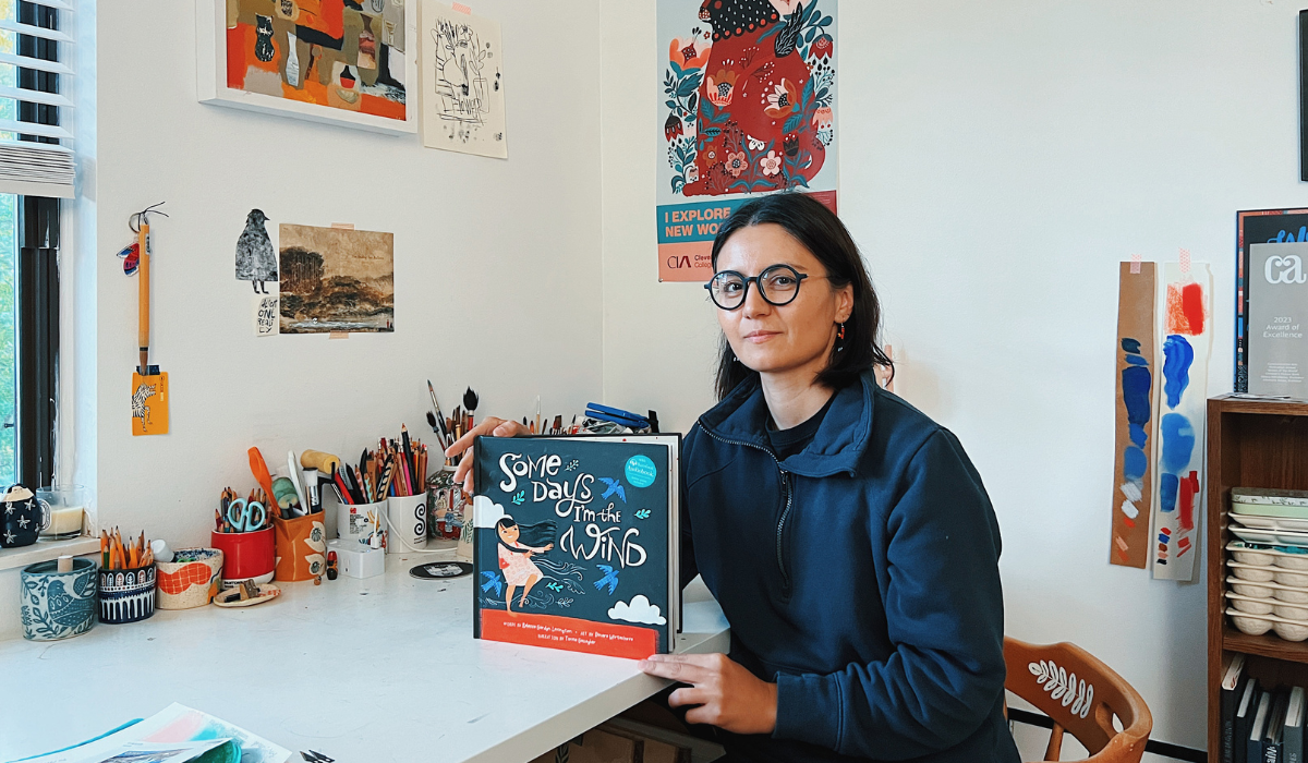Illustrator Dinara Mirtalipova holding her book, Some Days I'm the Wind